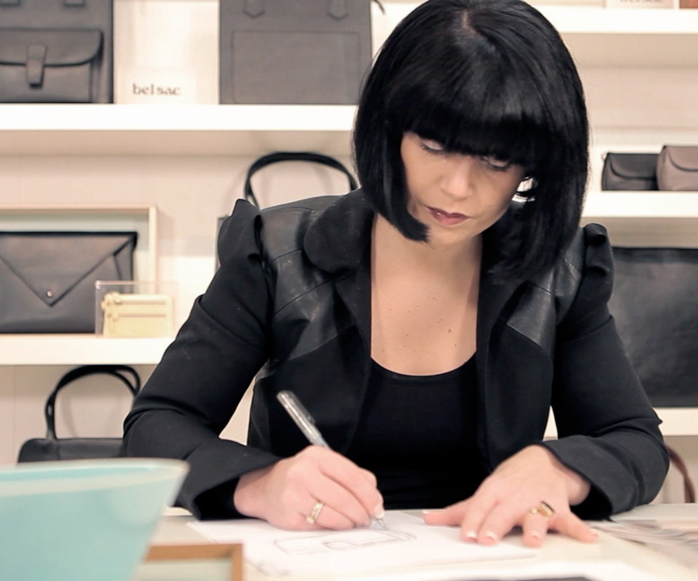 Get more done, faster and with less hassle Professional retailer in black business wear working on design at desk, handbags on shelves in background